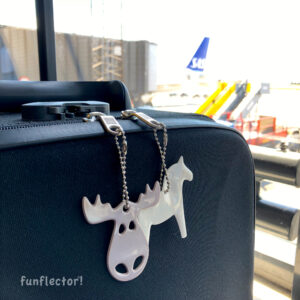 White dala horse safety reflector and brown moose safety reflector on a suitcase going to Sweden