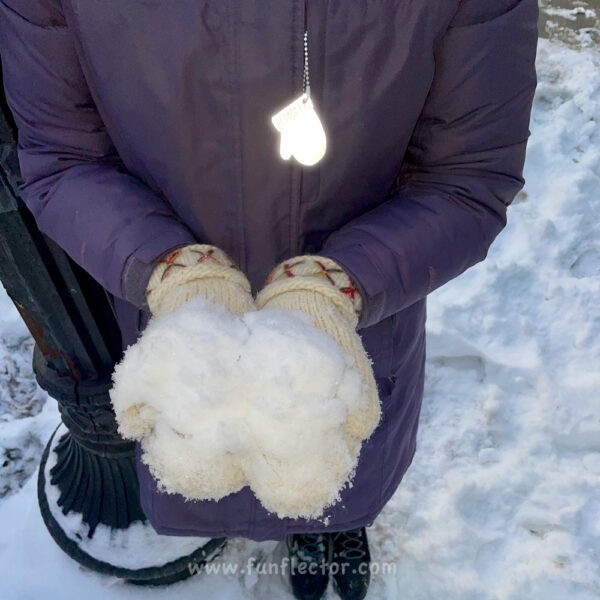 White mitten safety reflector on winter jacket zipper pull - night
