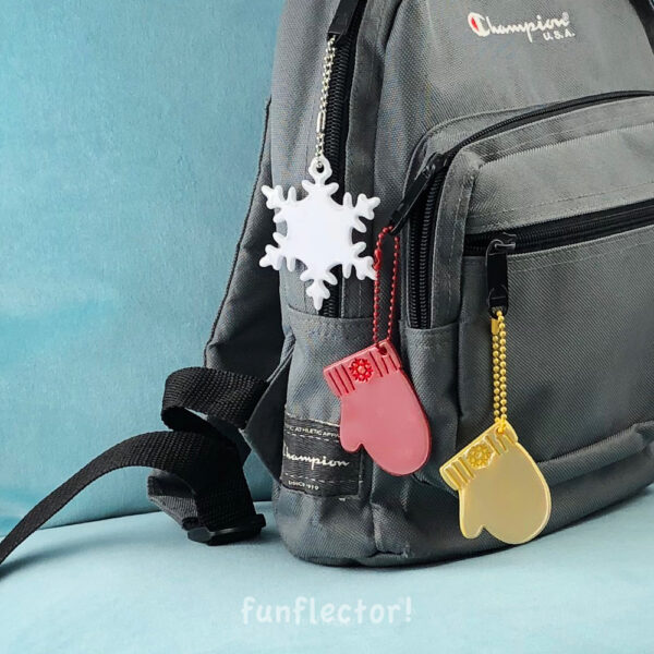 White snowflake and colorful mitten safety reflectors on backpack