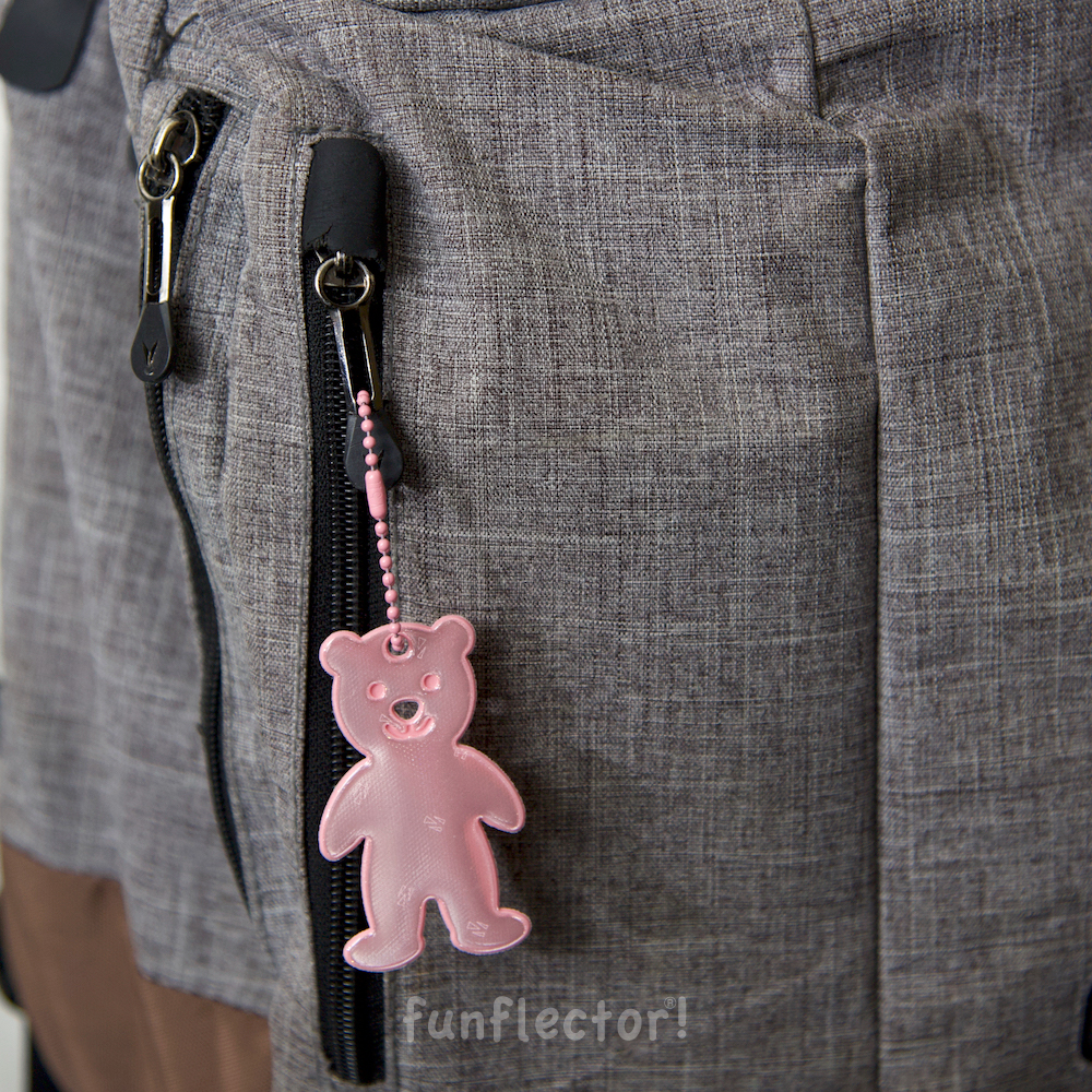 Pink teddybear safety reflector on gray backpack