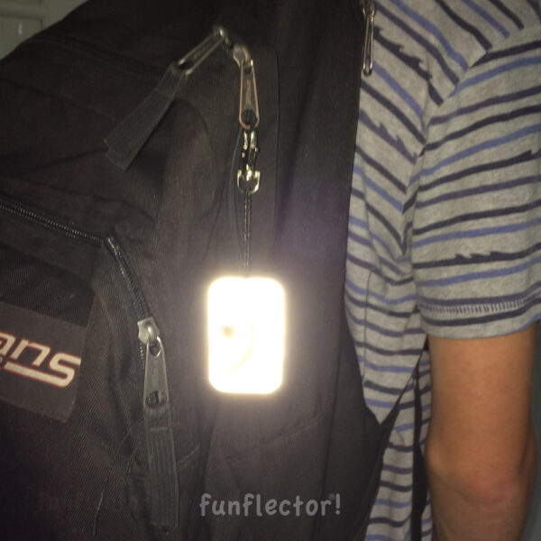 Bass clef safety reflector on backpack at night