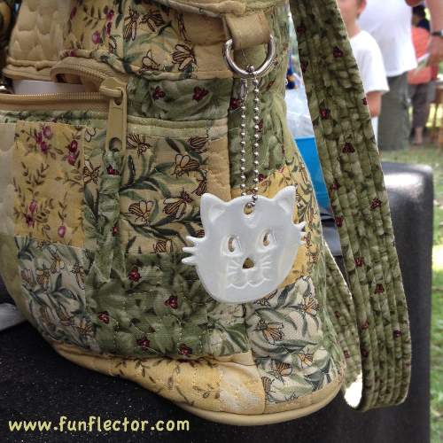 White kitten safety reflector on a floral purse.