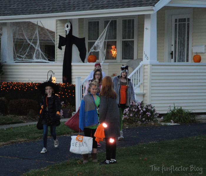 Children trick-or-treating in the neighborhood. Some with safety reflectors some without. Halloween safety 2021 is both about staying away from the Covid-19 virus and be visible in traffic.