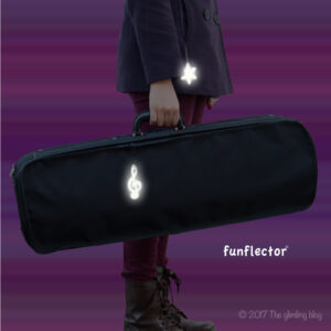 Treble clef and snowflake safety reflector on instrument case at night by funflector